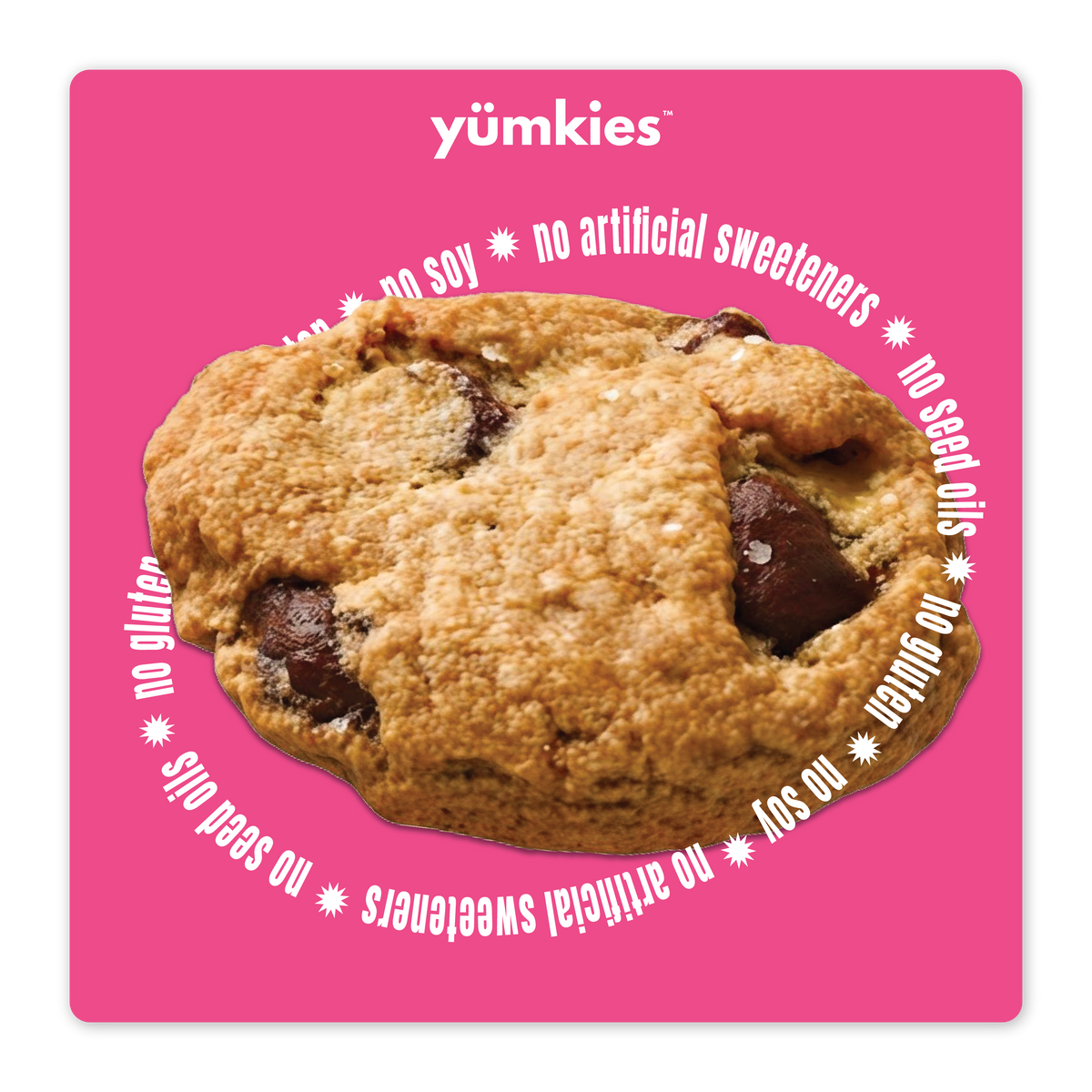 A chocolate chip cookie centered on a bright pink square background with white text reading yumkies at the top and 'no soy * no artificial sweeteners * no seed oils * no gluten  * no soy around the cookies